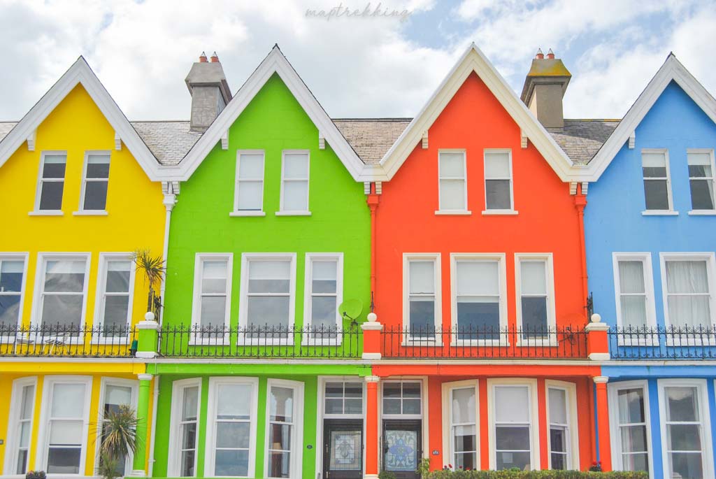 the cute town of Whitehead Belfast has bright colorful houses with a bright blue sky and clouds in the background making you ever wonder why you asked is Northern Ireland safe to visit?