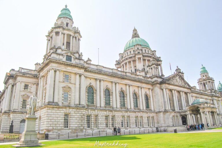 you might be wondering, is Northern Ireland safe? or is Northern Ireland dangerous? taking a walk through belfast and ending up at the belfast city hall that is pictured will tell you all you need to know as the sun shines down onto this government building that is surronded by green grass statues and benches