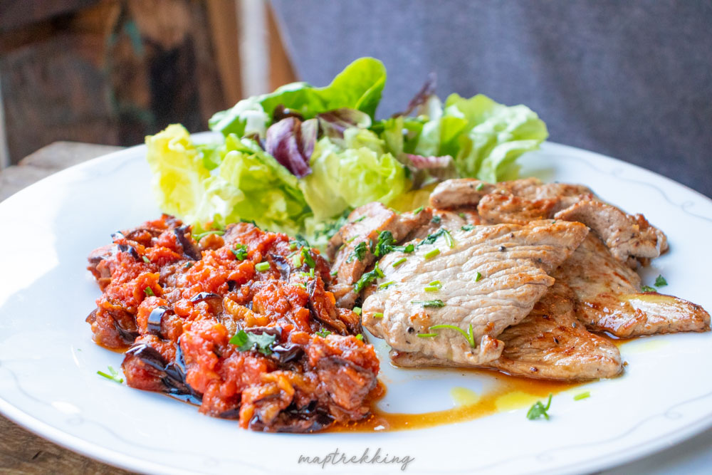 a traditional Montenegro food dish with veal tomato and eggplant with a side salad