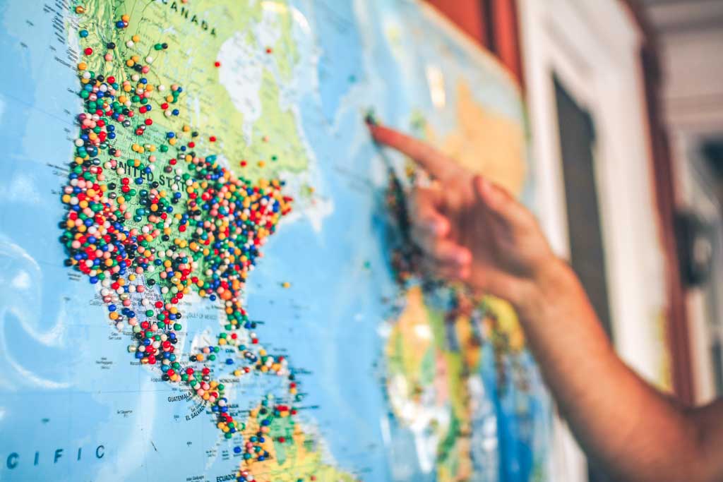 pinning pins on a map because a traveler is realizing that travel is good for the soul